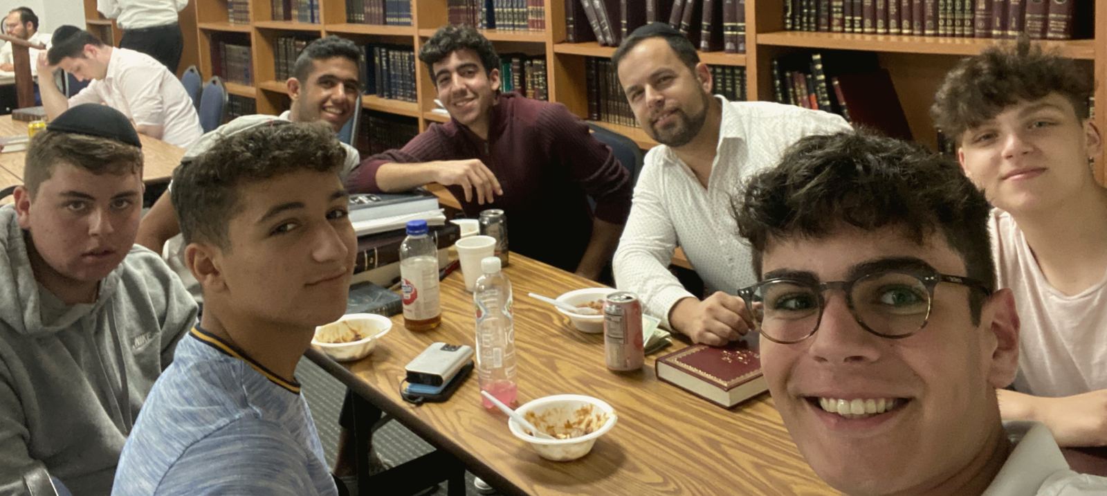 Talmidim and their rebbe smiling around a table