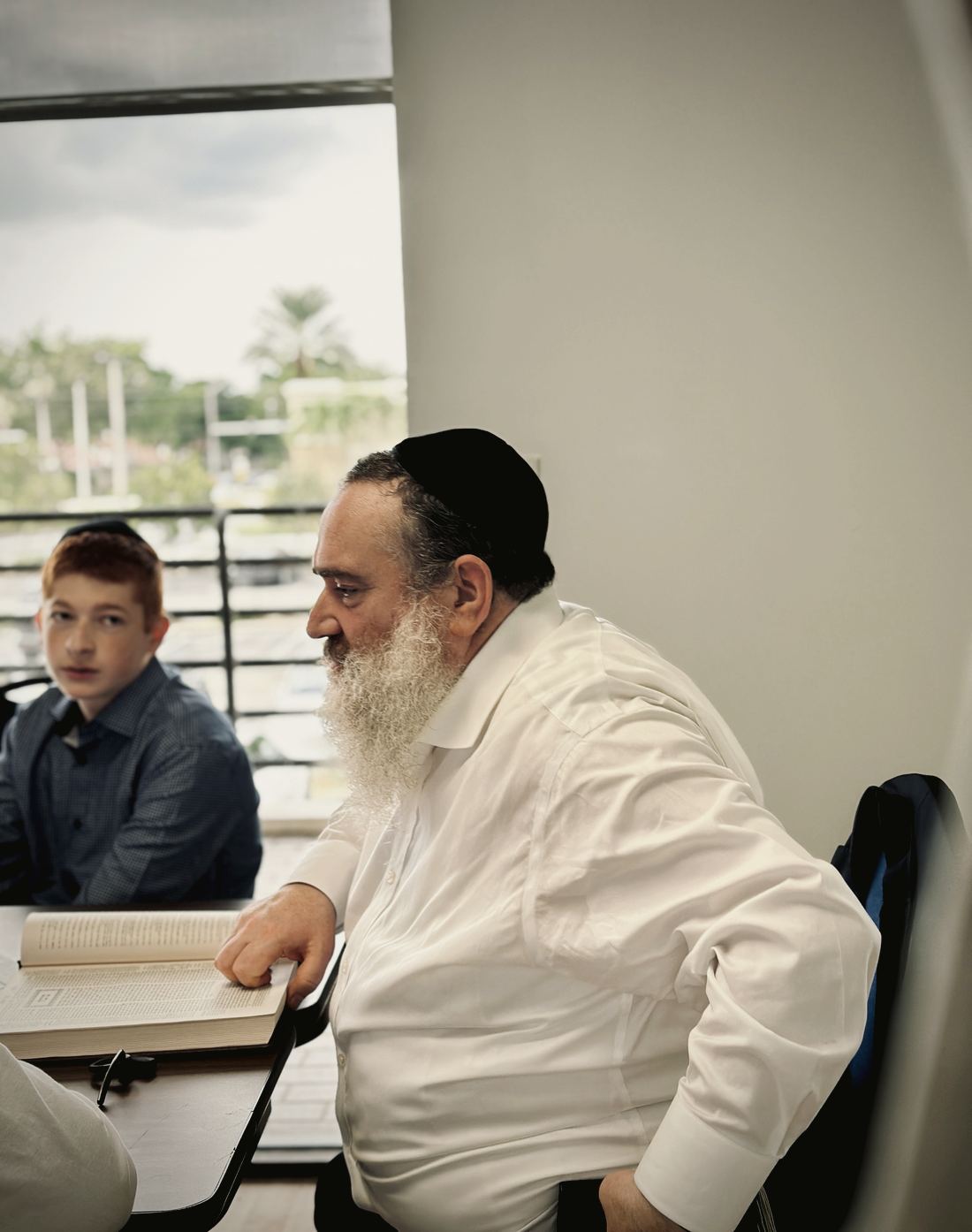 A rebbe learning with a talmid by the window